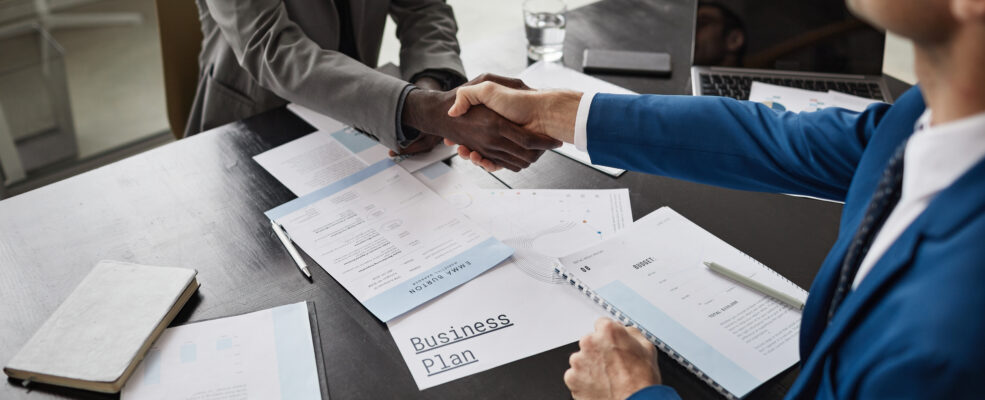 Close up shot of businessmen shaking hands over a desk to symbolise hiring new talent